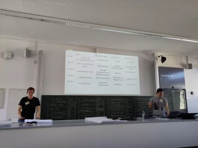 Bild der Sessionplanung. links und rechts sind zwei Personen zu sehen. In der Mitte ist die Projektion des Sessionplans zu sehen.